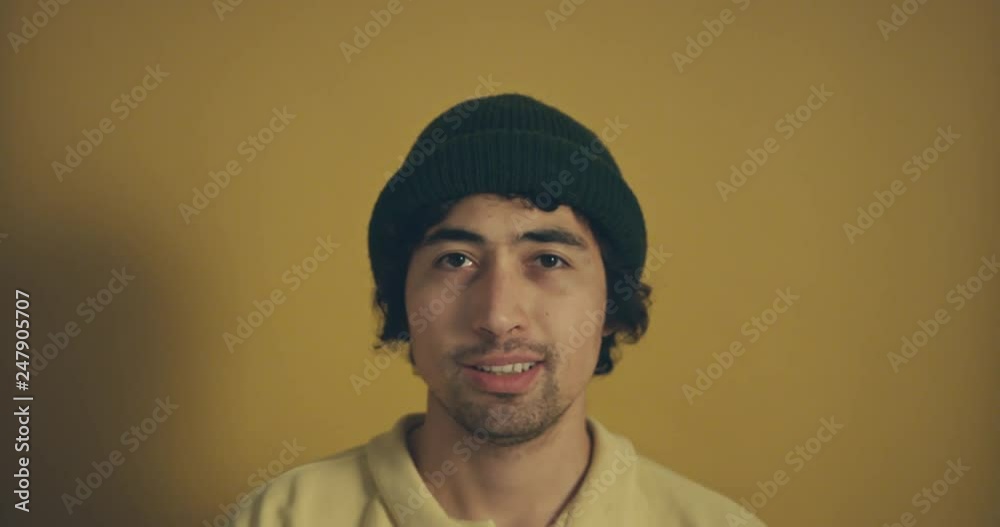Young man with beanie against yellow background