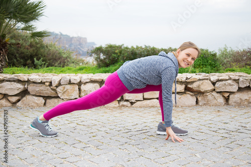 Happy sporty young woman stretching legs outdoors