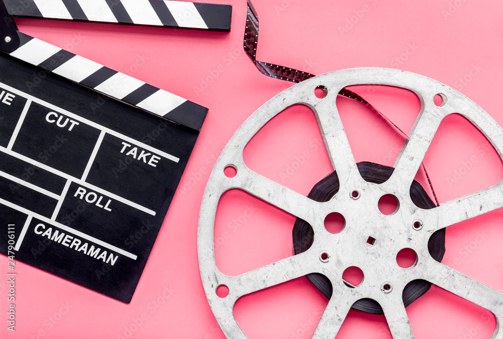 Filmings concept. Clapperboard and film stock on pink background top view