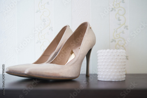 golden female shoes on a high hairpin next to a decorative white candle