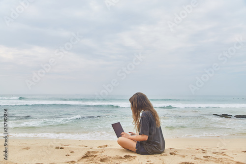 Young girl working at the computer on the beach. The freelancer working on the beach. © Dima Anikin
