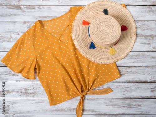 Womens clothing  accessories   yellow blouse in polka dot  straw hat . Fashion outfit  spring summer collection. Shopping concept. Flat lay  view from above