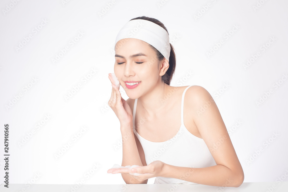 Beautiful woman is washing her face on white background Beautiful woman is washing her face on white background