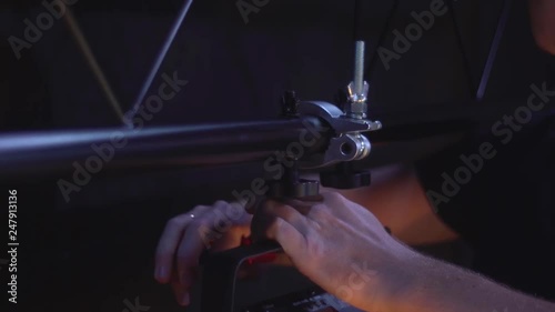 Light technician attaches the spotlight screw to the base of the stage to illuminate hall. work backstage