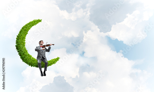 Handsome violinist on moon in blue sky play his melody