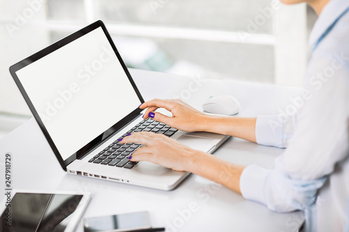 Place of work. Young adult girl using computer. Business woman working at laptop with white blank empty screen