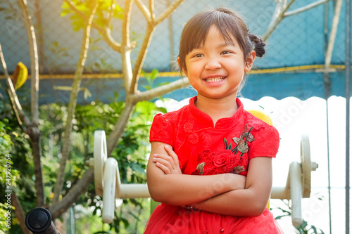 Asian child girl smiling in red dress and cross one's arm, Concept costume Chinese new year