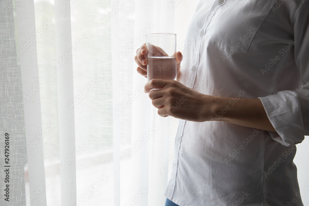 young woman drinking mineral water on white curtain windows texture background. young woman drinking mineral water on white curtain windows texture background.