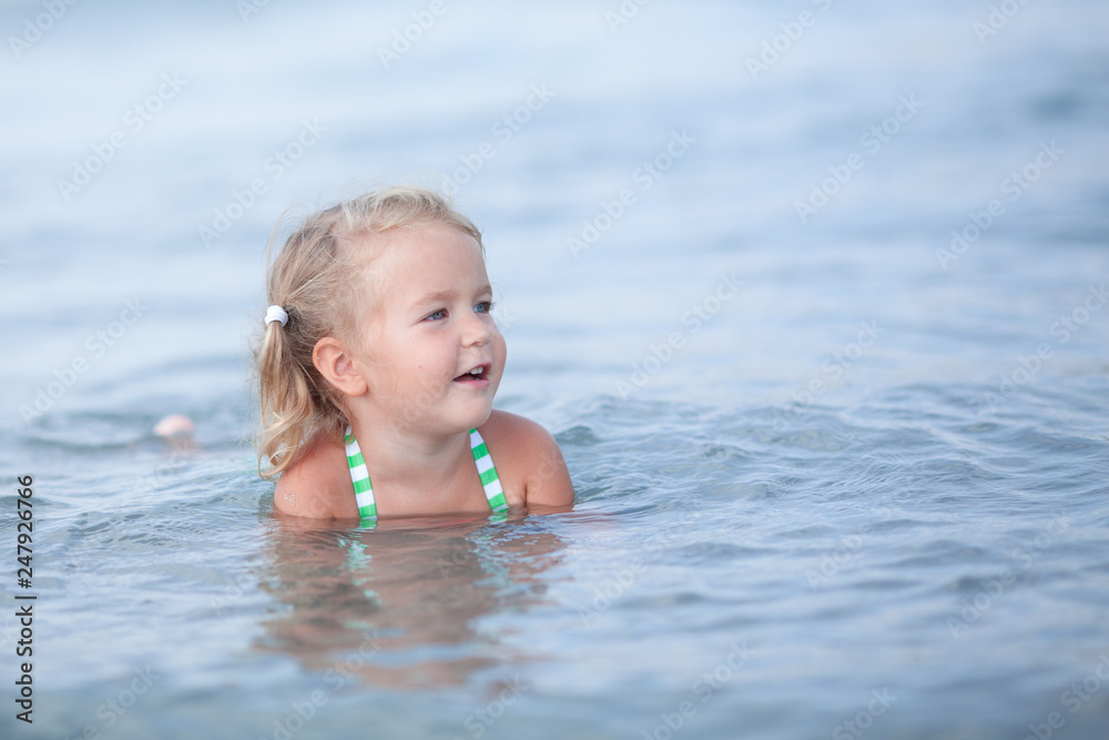 Little cute happy girl swims in the sea, Spain