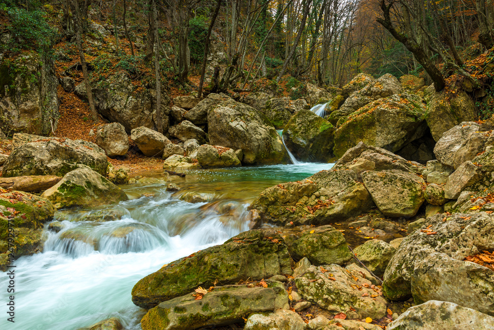 Autumn landscape - large boulders in the gorge of the mountains, where the fast cold river flows Autumn landscape - large boulders in the gorge of the mountains, where the fast cold river flows
