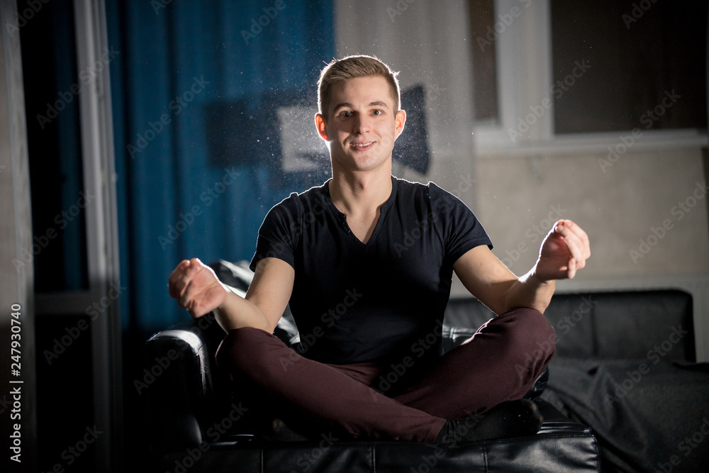 Fototapeta premium Young attractive smiling guy sitting in lotus pose
