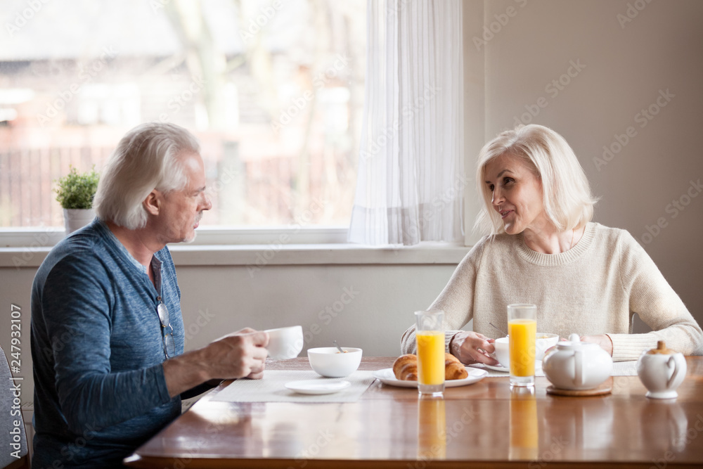 Senior wife and husband talking during breakfast in the morning Senior wife and husband talking during breakfast in the morning