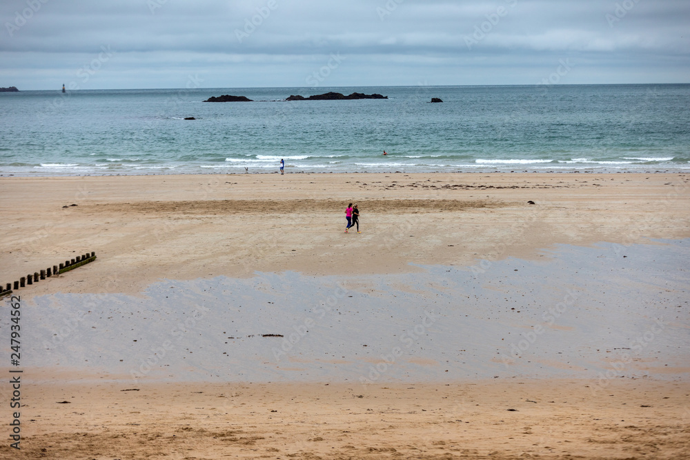Saint-Malo, France - September 12, 2018: Women are running  along the beach in Saint-Malo, Brittany, France