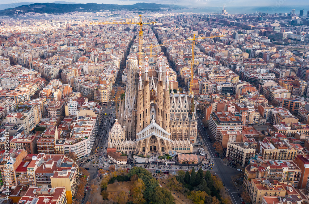 Aerial; drone view of main Gaudi project Sagrada Familia Temple; majestic  building towering over the rooftops of Eixample district; long construction  of the temple "business card" of Barcelona, Spain foto de Stock