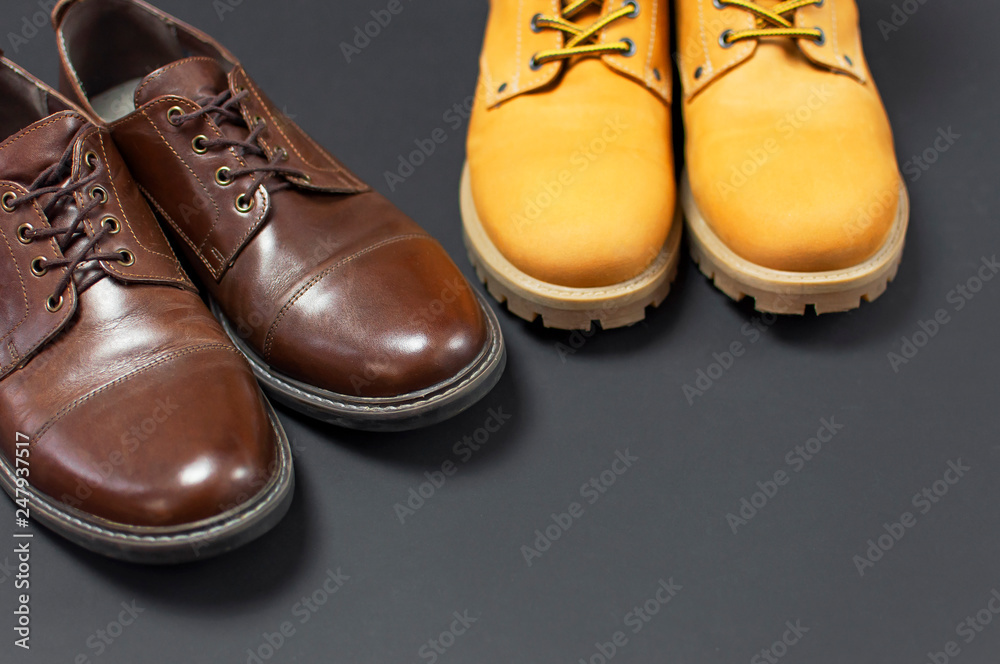 Classic brown leather men's shoes and Yellow men's work boots from natural nubuck on gray black background top view flat lay copy space. Fashion male concept, genuine leather shoes, sale, shop.