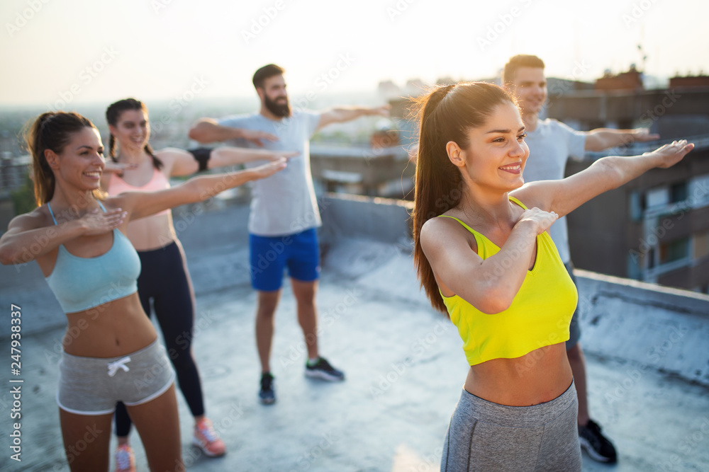 Group of happy fit young people friends in sportswear doing exercises . Sport outdoors Group of happy fit young people friends in sportswear doing exercises . Sport outdoors