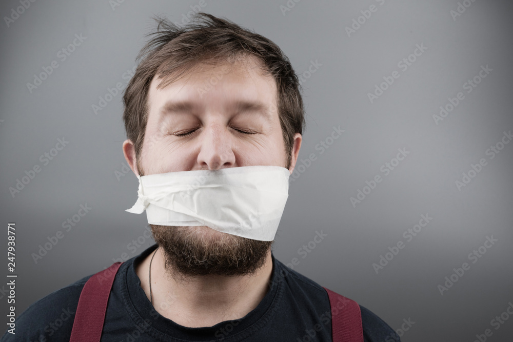 a man of European appearance with closed eyes and disheveled hair on his head, his mouth taped a man of European appearance with closed eyes and disheveled hair on his head, his mouth taped