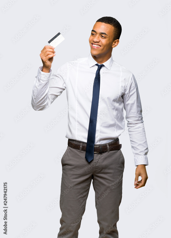 Young afro american businessman holding a credit card and thinking on isolated background Young afro american businessman holding a credit card and thinking on isolated background