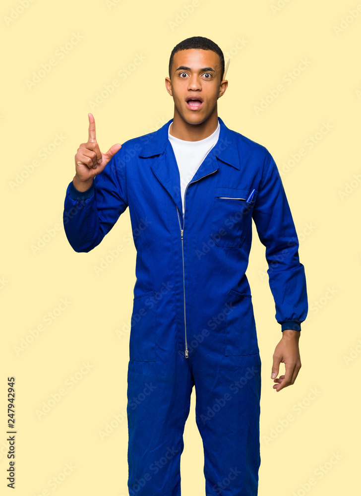 Young afro american worker man thinking an idea pointing the finger up on isolated background
