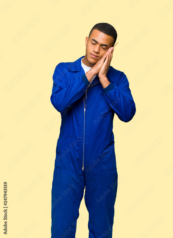 Young afro american worker man making sleep gesture in dorable expression on isolated background Young afro american worker man making sleep gesture in dorable expression on isolated background