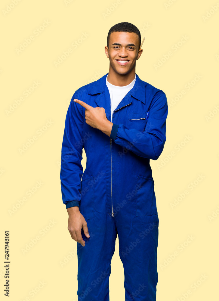 Fototapeta premium Young afro american worker man pointing to the side to present a product on isolated background