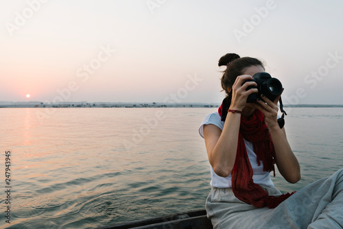 Photography Female photographer sitting on a boat on the River Ganges