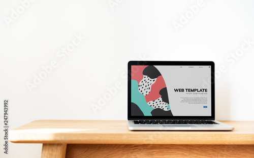 Laptop showing website template on a wooden table