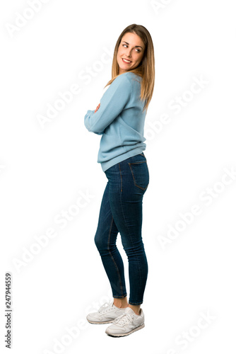 Full body of Blonde woman with blue shirt looking over the shoulder with a smile on white background
