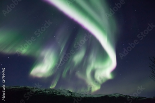 northern lights in Norway in green, blue and violet colours and mountains in the distance