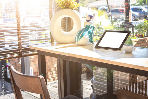 Digital tablet with blank screen on wooden table in coffee shop.
