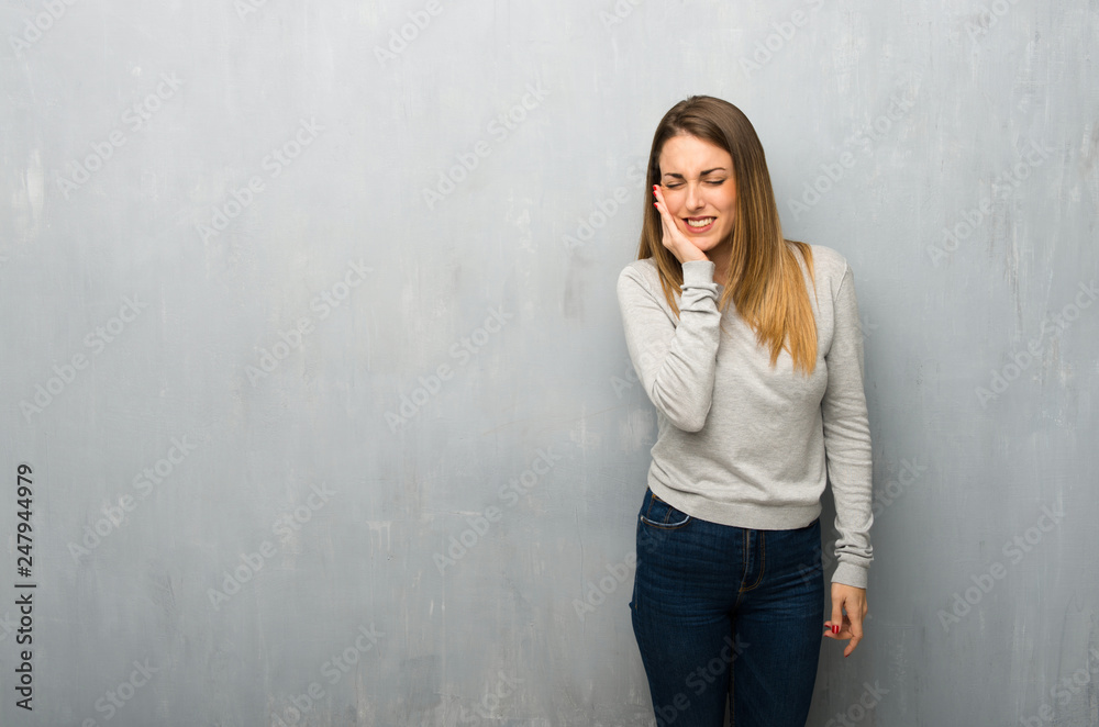 Young woman on textured wall with toothache Young woman on textured wall with toothache