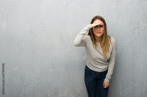 Young woman on textured wall looking far away with hand to look something
