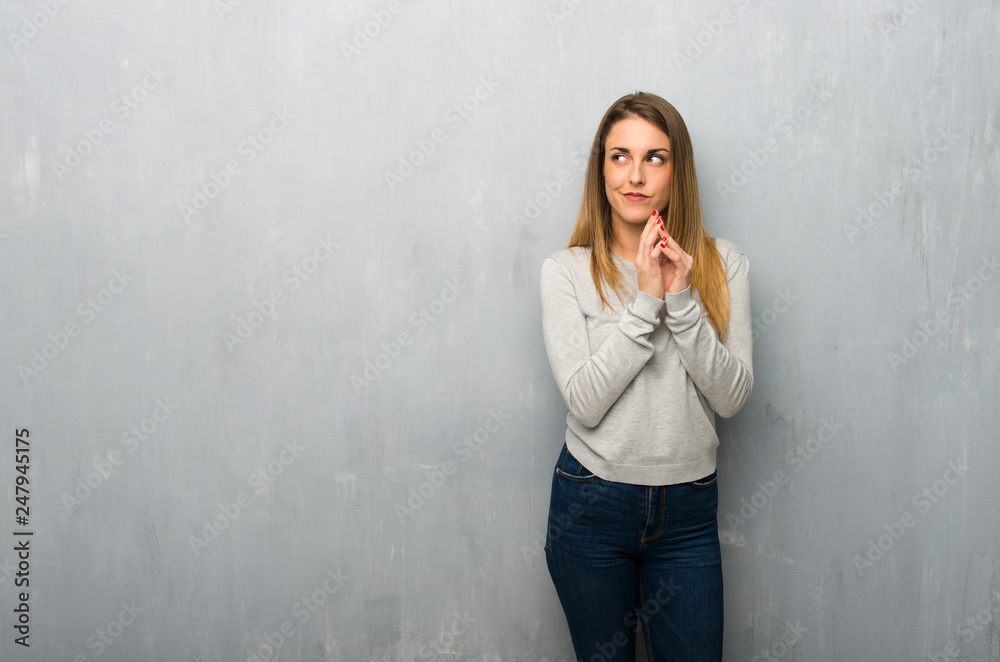 Young woman on textured wall scheming something Young woman on textured wall scheming something