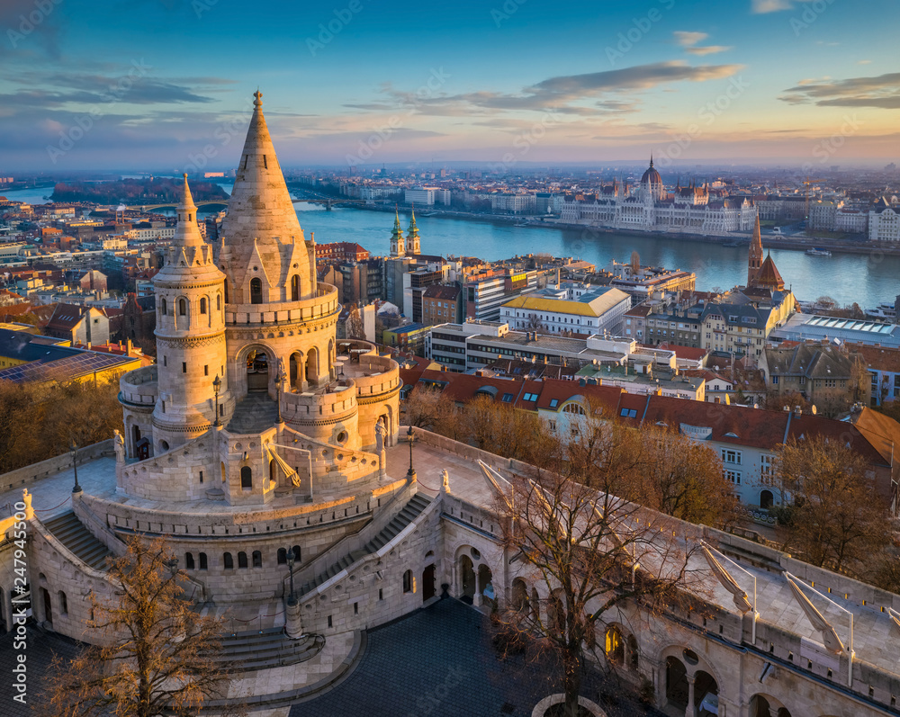 Naklejka premium Budapeszt, Węgry - główna wieża słynnego Baszty Rybackiej (Halaszbastya) z góry z budynkiem Parlamentu i rzeką Dunaj w tle w słoneczny poranek