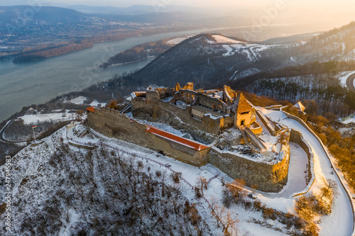 Visegrad, Hungary - Aerial view of the beautiful snowy high castle of Visegrad at sunrise with Dunakanyar at background. Winter morning photo