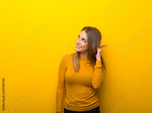 Young woman on yellow background thinking an idea while scratching head