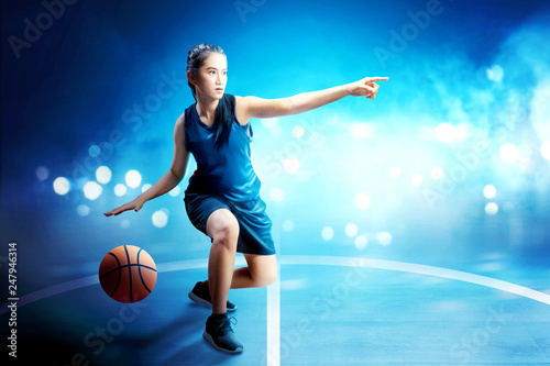 Beautiful asian woman in basketball uniform dribbling the ball