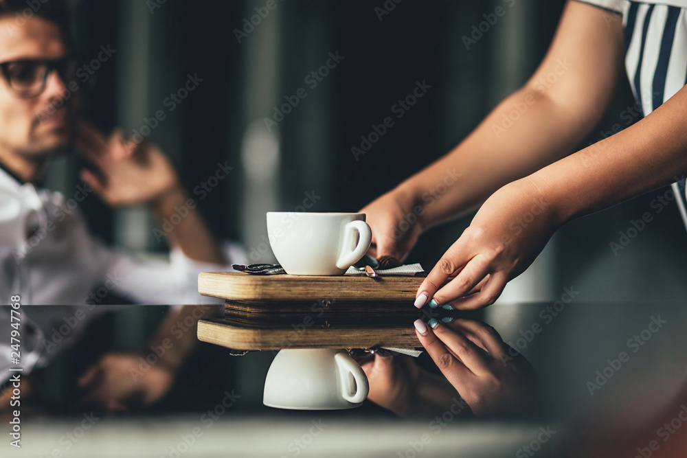 The waiter hands has brought to the client the order in cafe. Selective focus