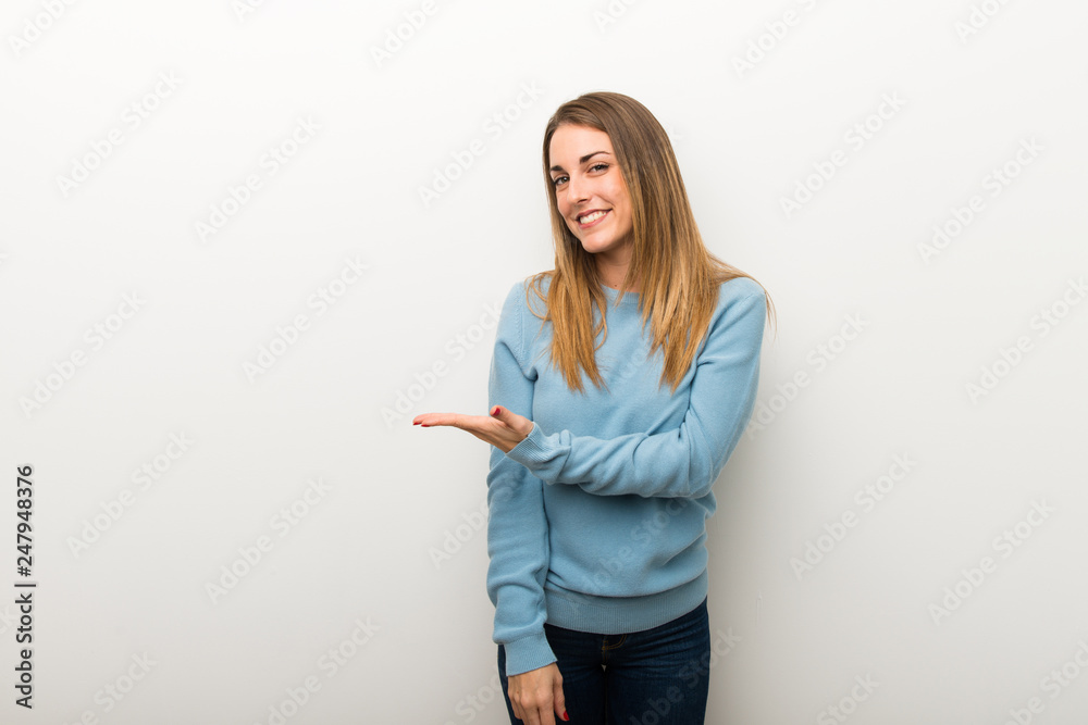Blonde woman on isolated white background presenting an idea while looking smiling towards Blonde woman on isolated white background presenting an idea while looking smiling towards