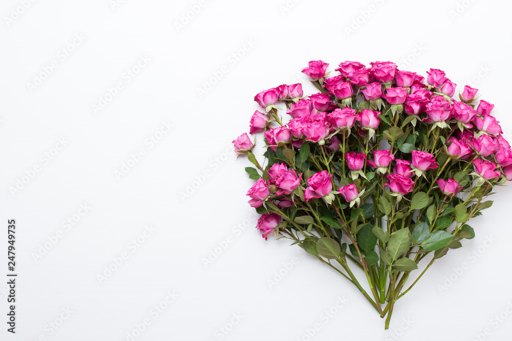 Flowers composition. Frame made of red rose on white wooden background. Flat lay, top view, copy space.