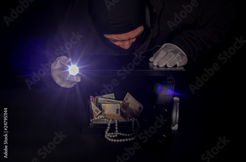 thief stealing valuables from safe at crime scene