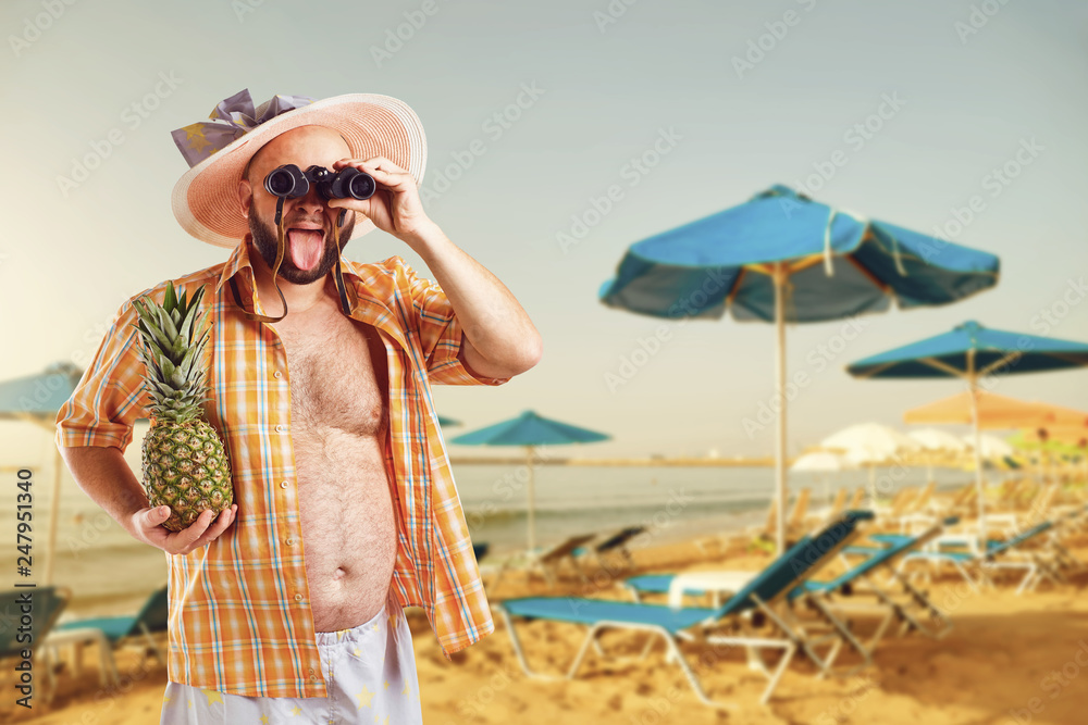 Funny fat bearded man with binoculars on vacation in  the beach in summer. 