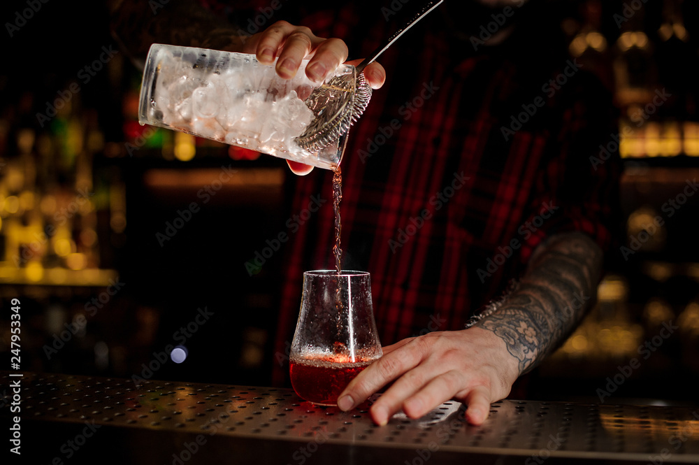 Mixologist pouring fresh and tasty bittersweet red cocktail
