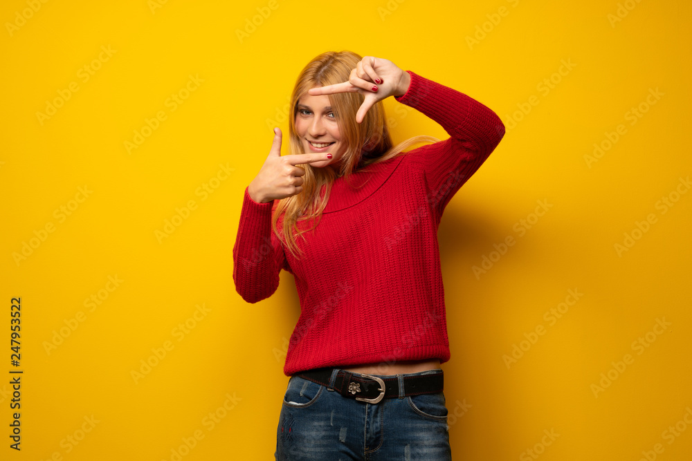 Blonde woman over yellow wall focusing face. Framing symbol