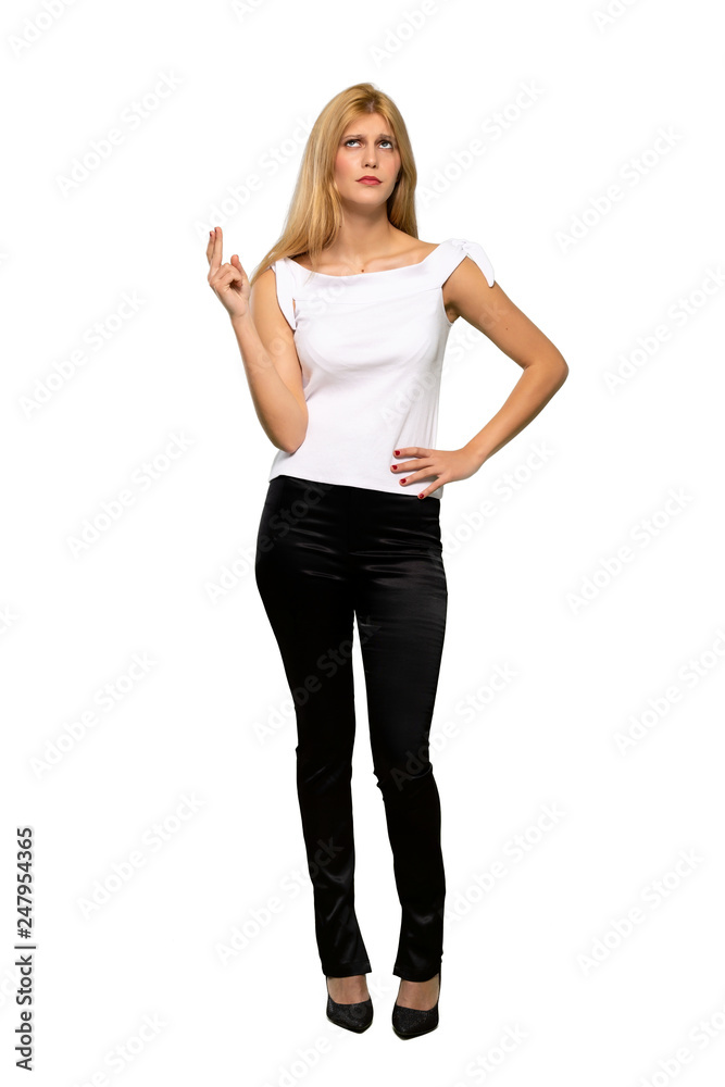 Young blonde woman with fingers crossing and wishing the best over isolated white background Young blonde woman with fingers crossing and wishing the best over isolated white background