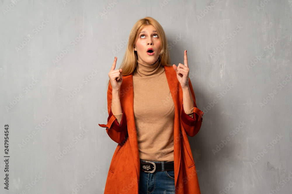 Woman over textured background pointing up and surprised Woman over textured background pointing up and surprised