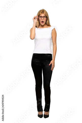Young blonde woman with glasses and surprised over isolated white background
