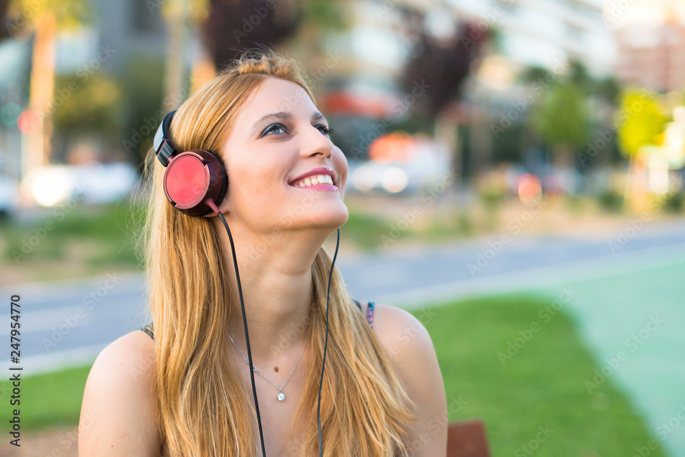 Φωτογραφία Happy pretty young teenager girl in a park listening to music with headphones