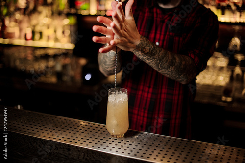 Fototapeta Naklejka Na Ścianę i Meble -  Barman stirring a fresh alcoholic juicy cocktail using a spoon