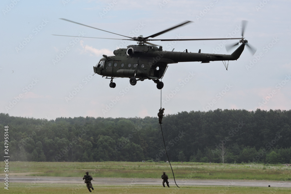 Deploying troops from a military helicopter using fast-roping technique - obrazy, fototapety, plakaty 